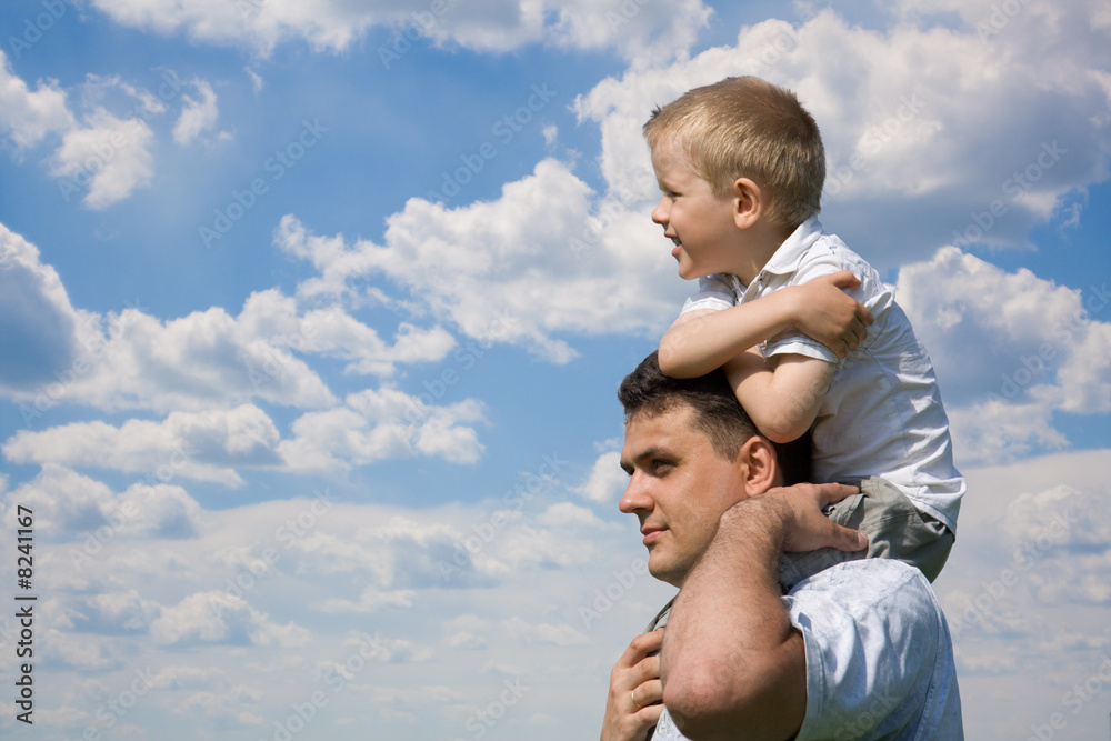 Little son sits on father`s shoulders