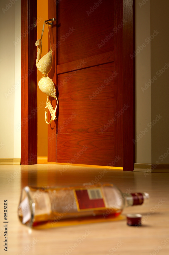 Bottle of whisky on a floor, a bra on a room door