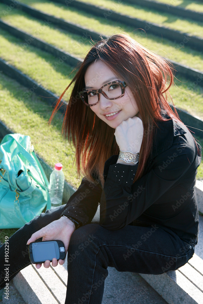 young asian women holding mobile phone sitting on stair