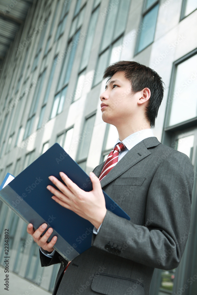 一位年轻的亚洲商人正在户外阅读文件