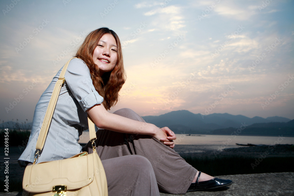 日落时海滩上美丽的年轻女子。