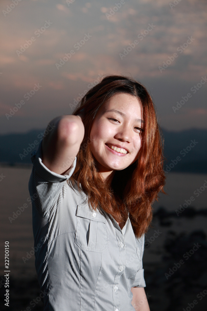 日落时海滩上美丽的年轻女子。