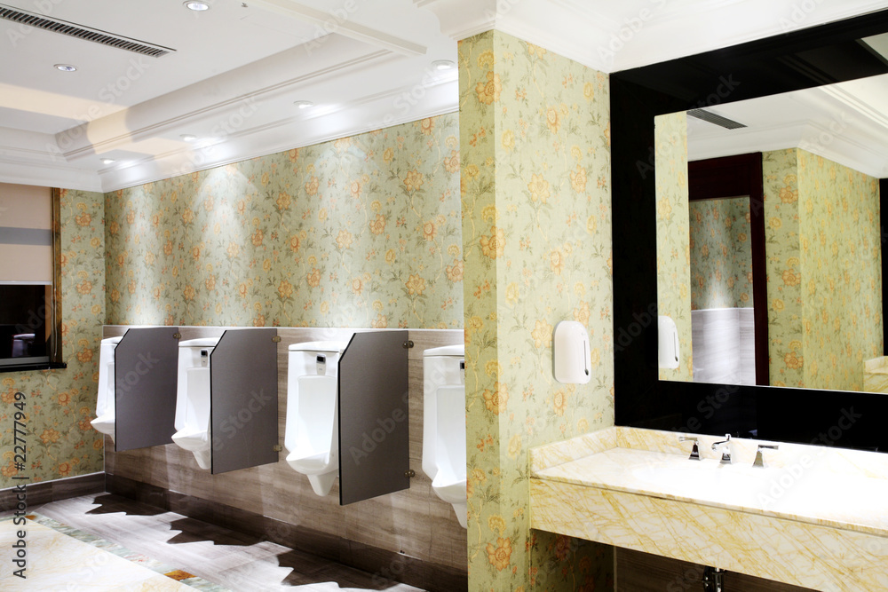 row of white toilets of  man restroom in the hotel .