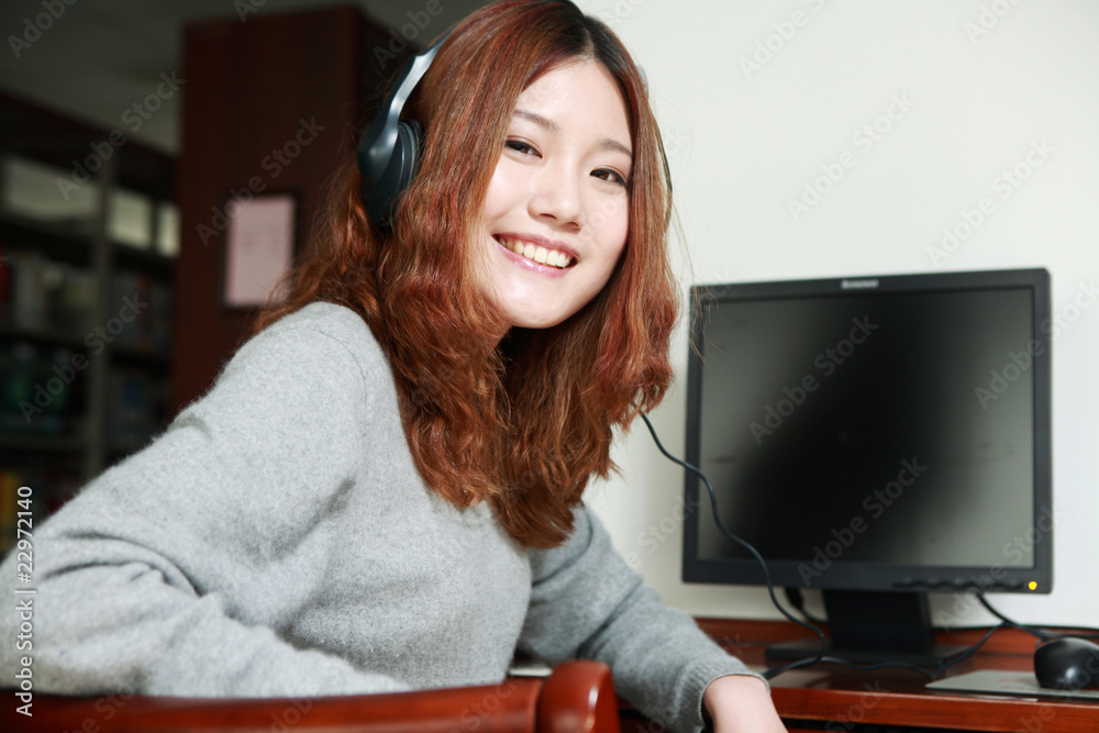 Asian girl sitting in front of the computer listening music