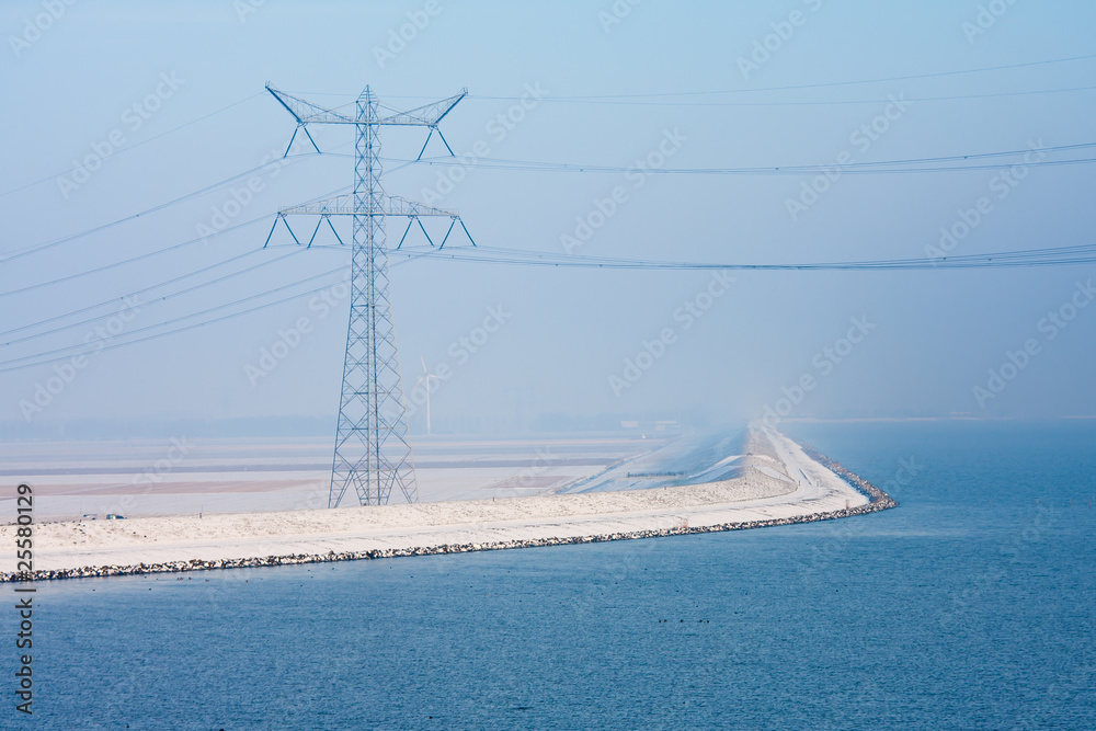 Endless Dutch snowy dike disappearing in winter haze