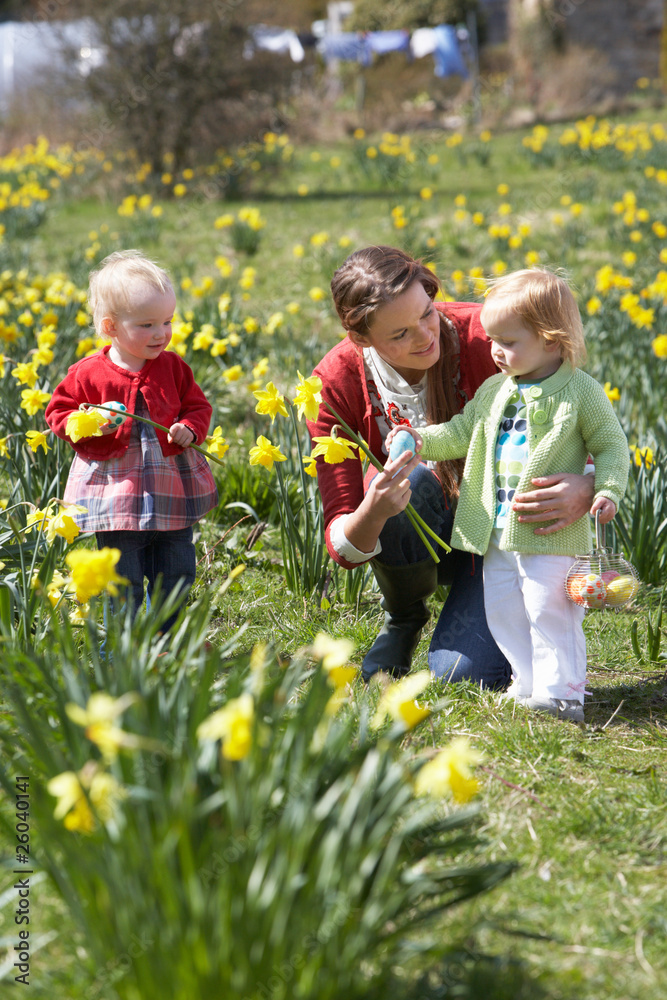 Mother And Children In Daffodil Field With Decorated Easter Eggs