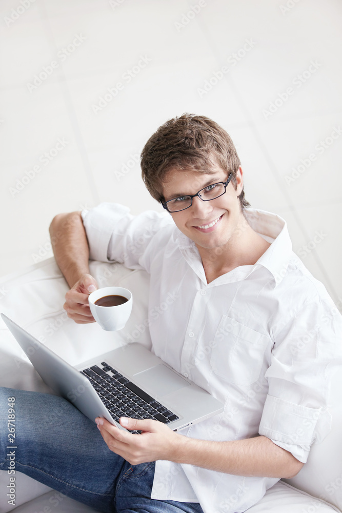 A young handsome man with a coffee and a laptop