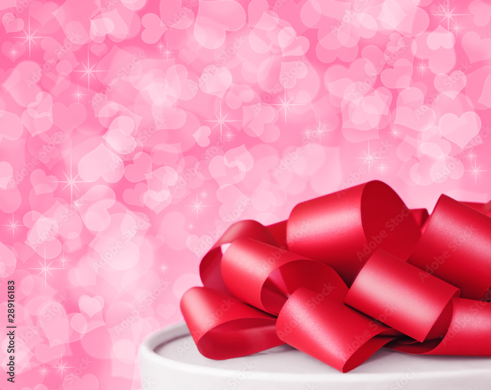 Top of valentines day gift box with big red ribbon on pink background with hearts all over it