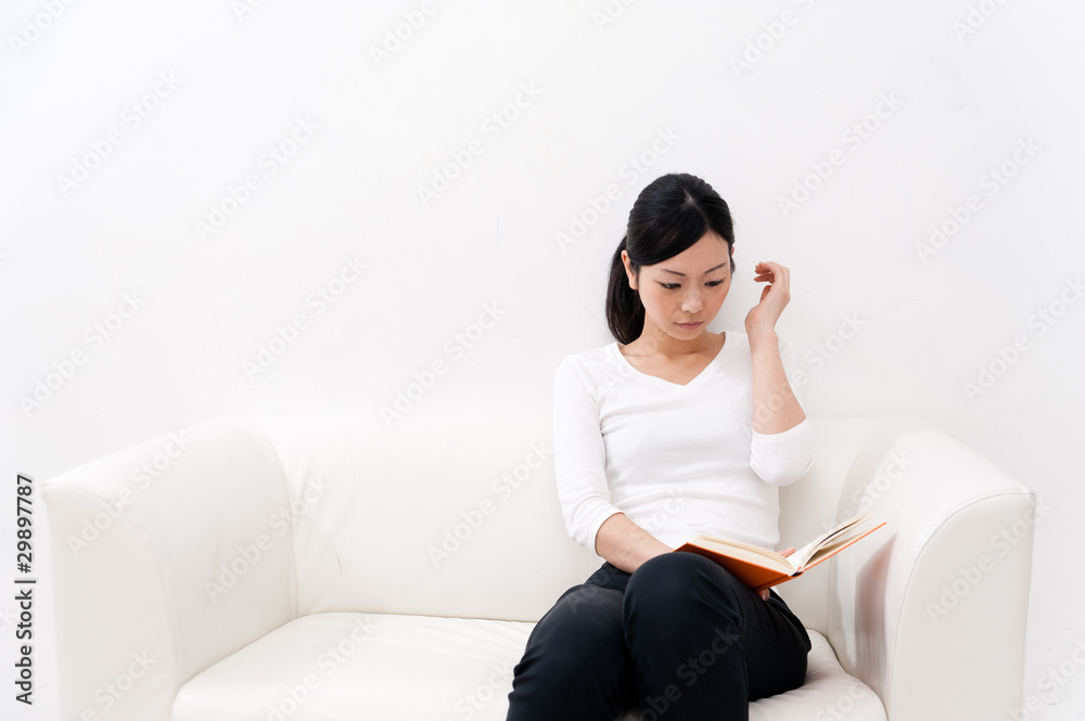 beautiful asian woman reading a book on the couch