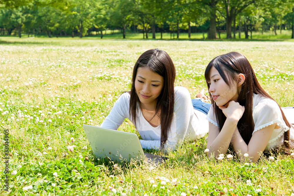 亚洲美女在公园里用笔记本电脑