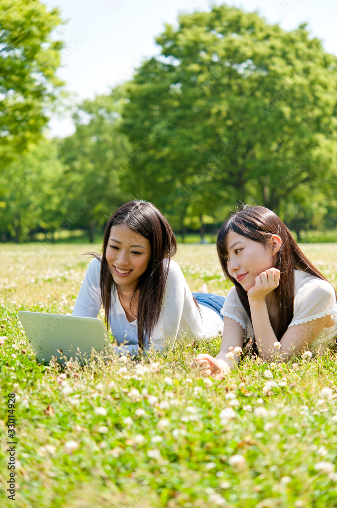 亚洲美女在公园里用笔记本电脑