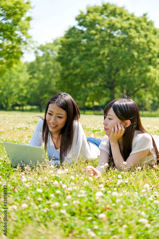 亚洲美女在公园里用笔记本电脑