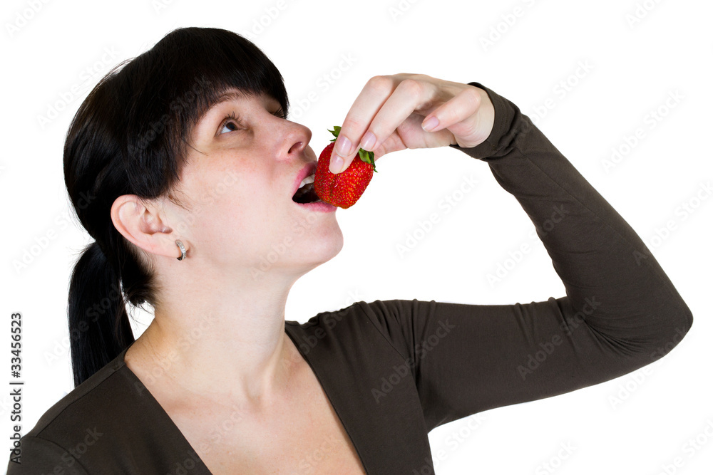 The girl eats a strawberry