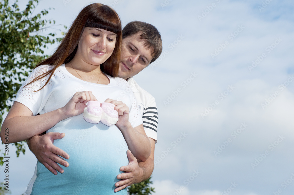 Man and a pregnant woman hugging in the park