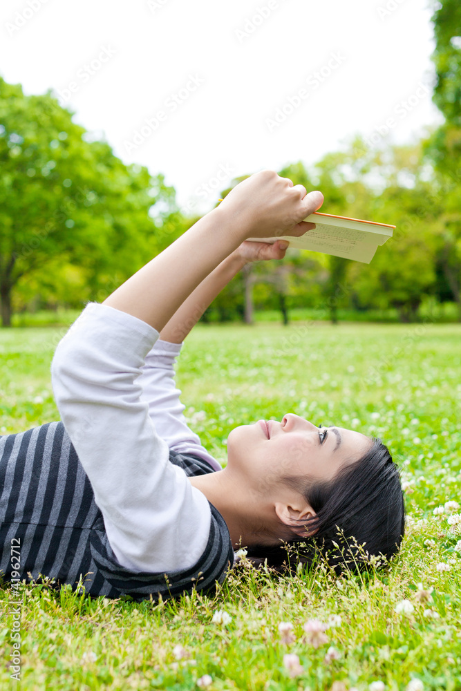 young asian woman reading book in the park