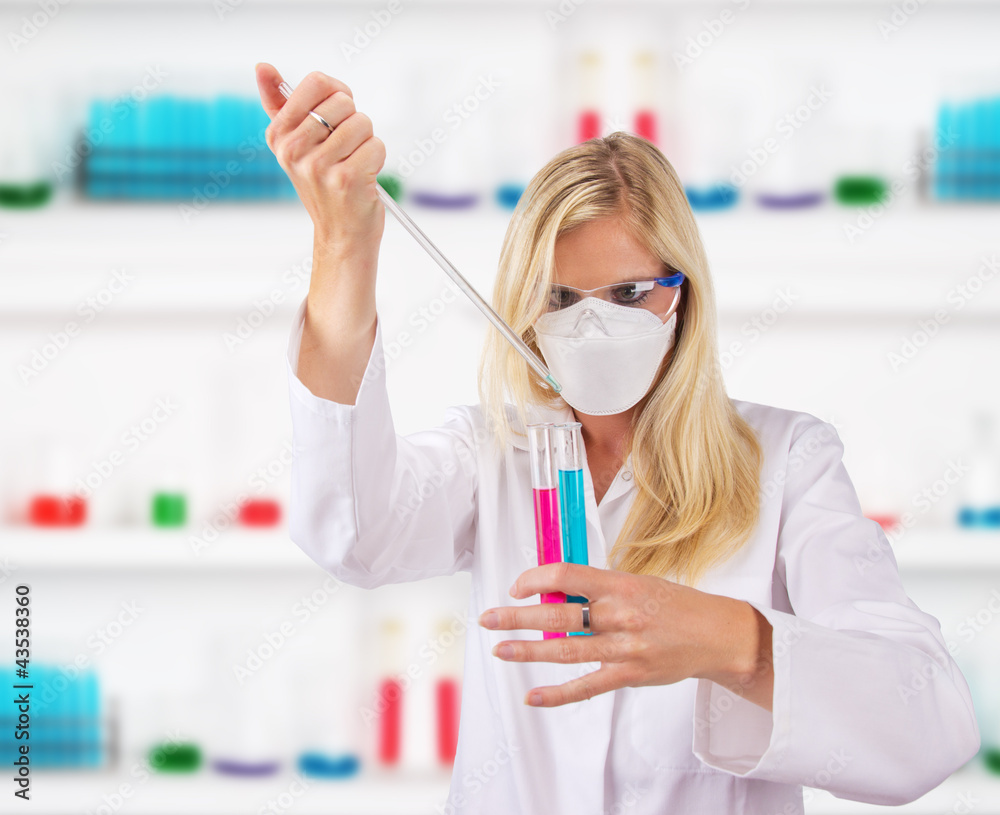 Young attractive laboratory assistant droping chemical liquid