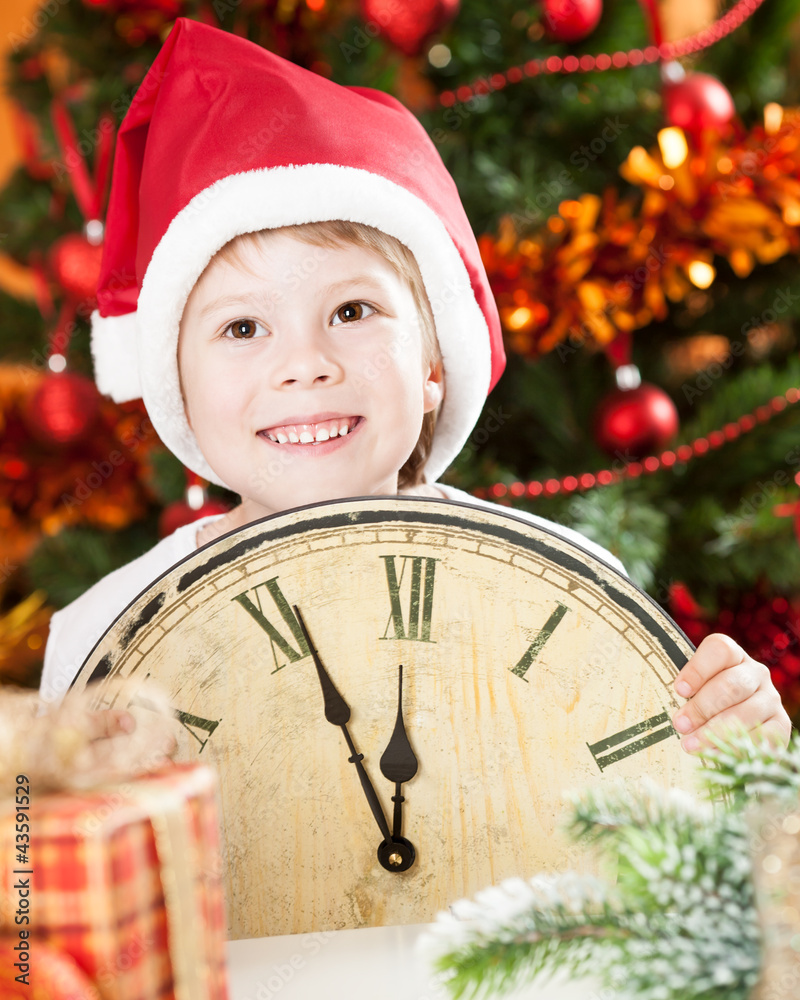 Kid in Santa`s hat holding vintage clock