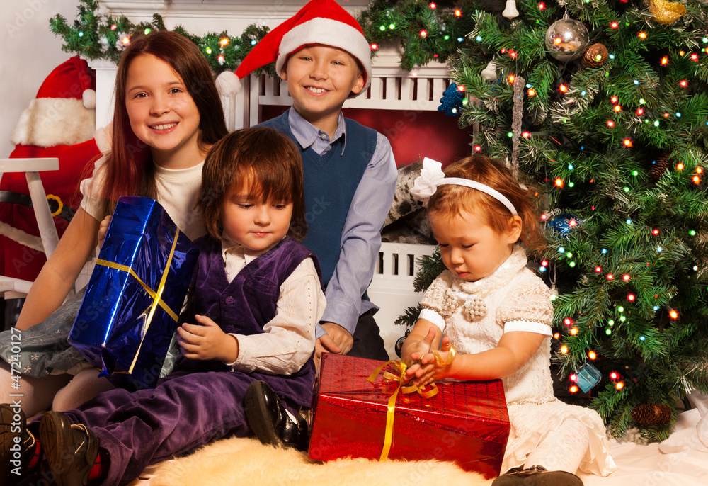 Four kids sitting side by side to fireplace