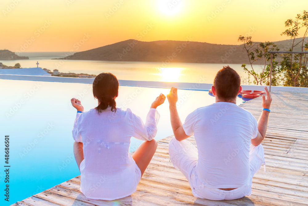 Couple meditating together at sunrise