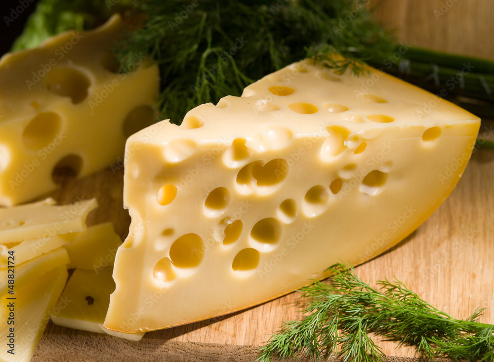 piece of cheese with dill on wooden table