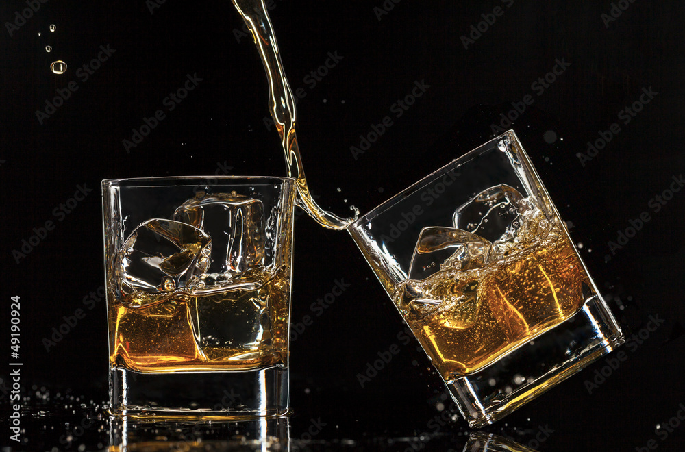 Pouring whiskey into glasses, isolated on black background