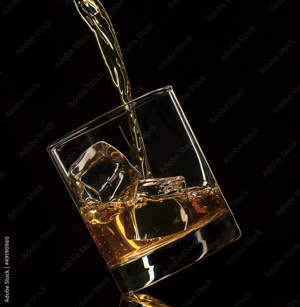 Pouring whiskey into glass, isolated on black background