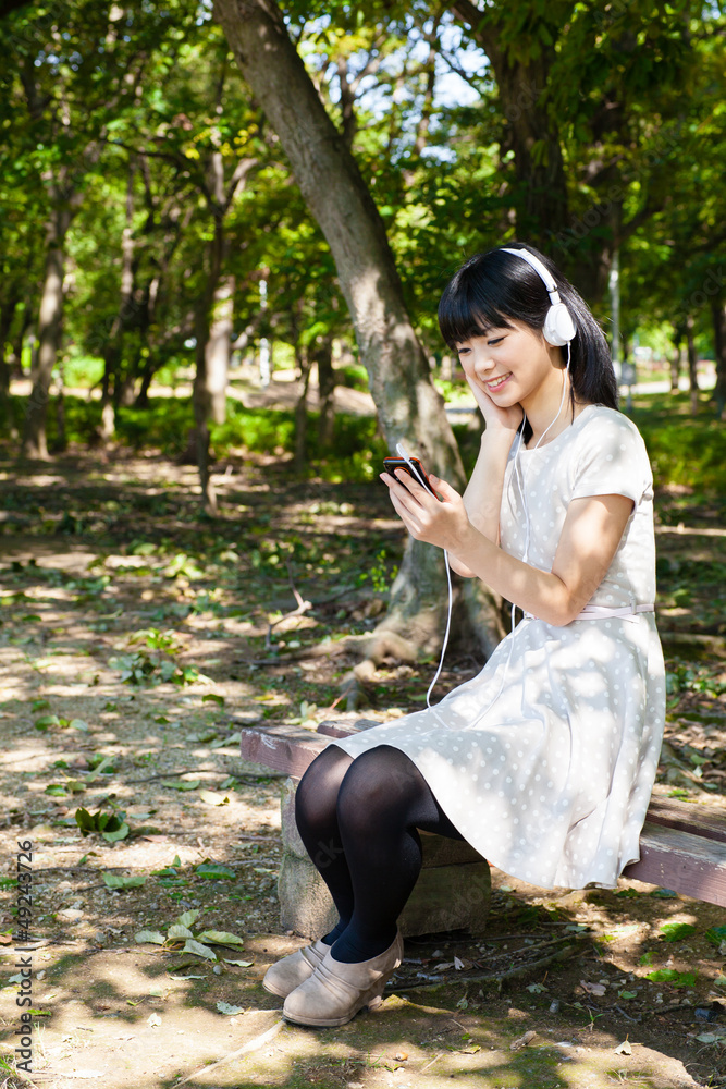 atractive asian woman listening music in the park