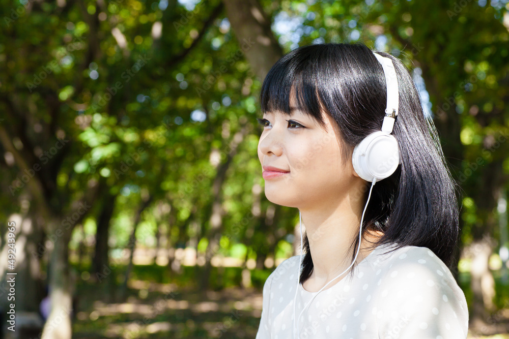 atractive asian woman listening music in the park