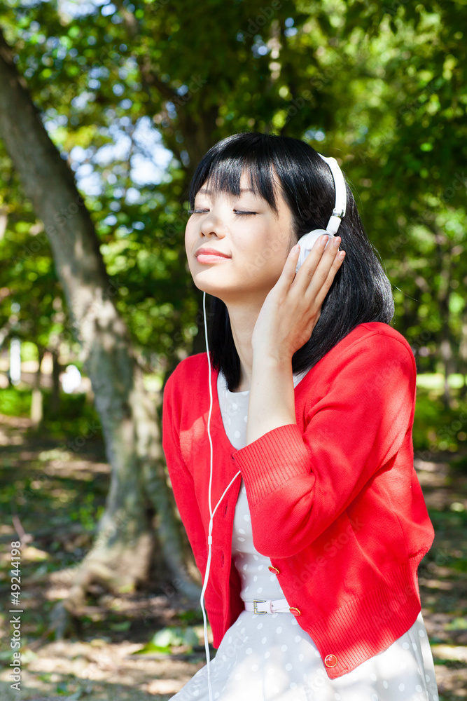 atractive asian woman listening music in the park