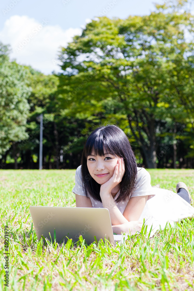 一名在公园里使用笔记本电脑的亚洲活跃女性