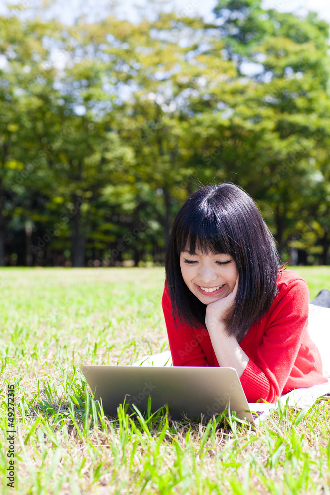 attractive asian woman using laptop in the park