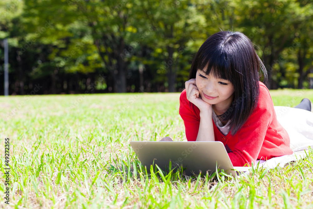 在公园里使用笔记本电脑的魅力亚洲女性