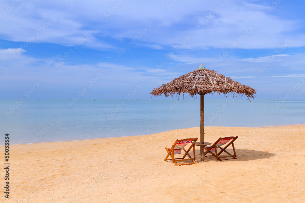 Tropical beach scenery with parasol and deck chairs in Thailand