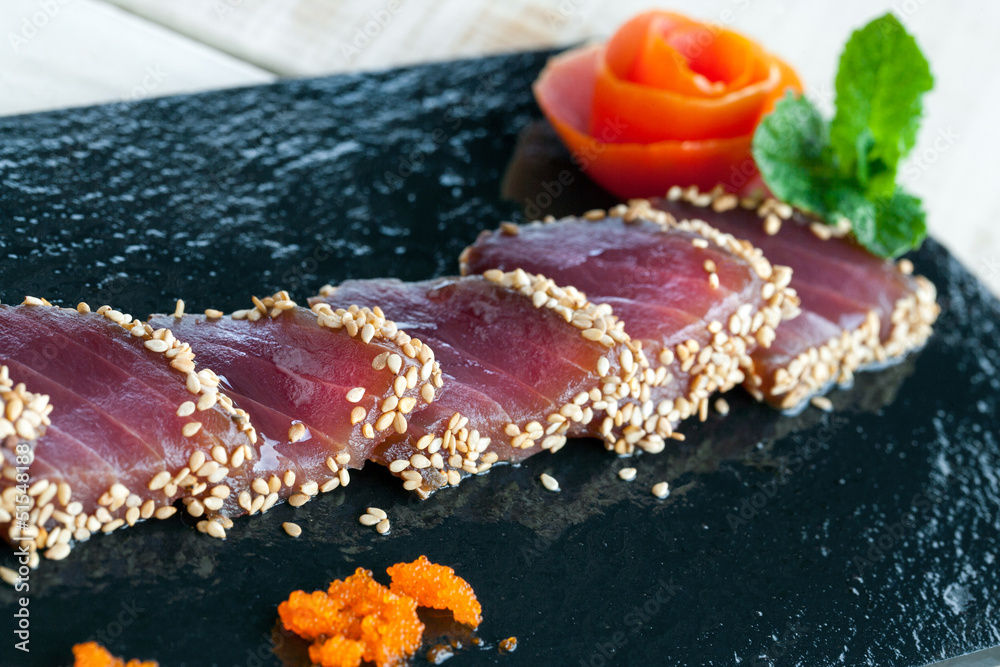 Japanese tataki served on black tile.