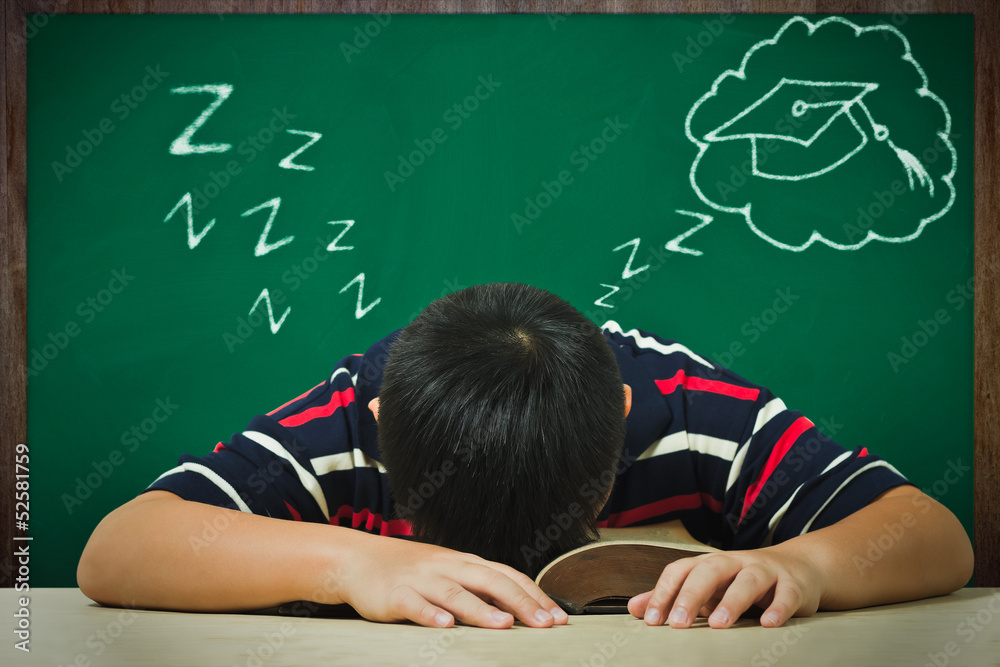 Asian boy sleeping on a book and dreaming of graduation