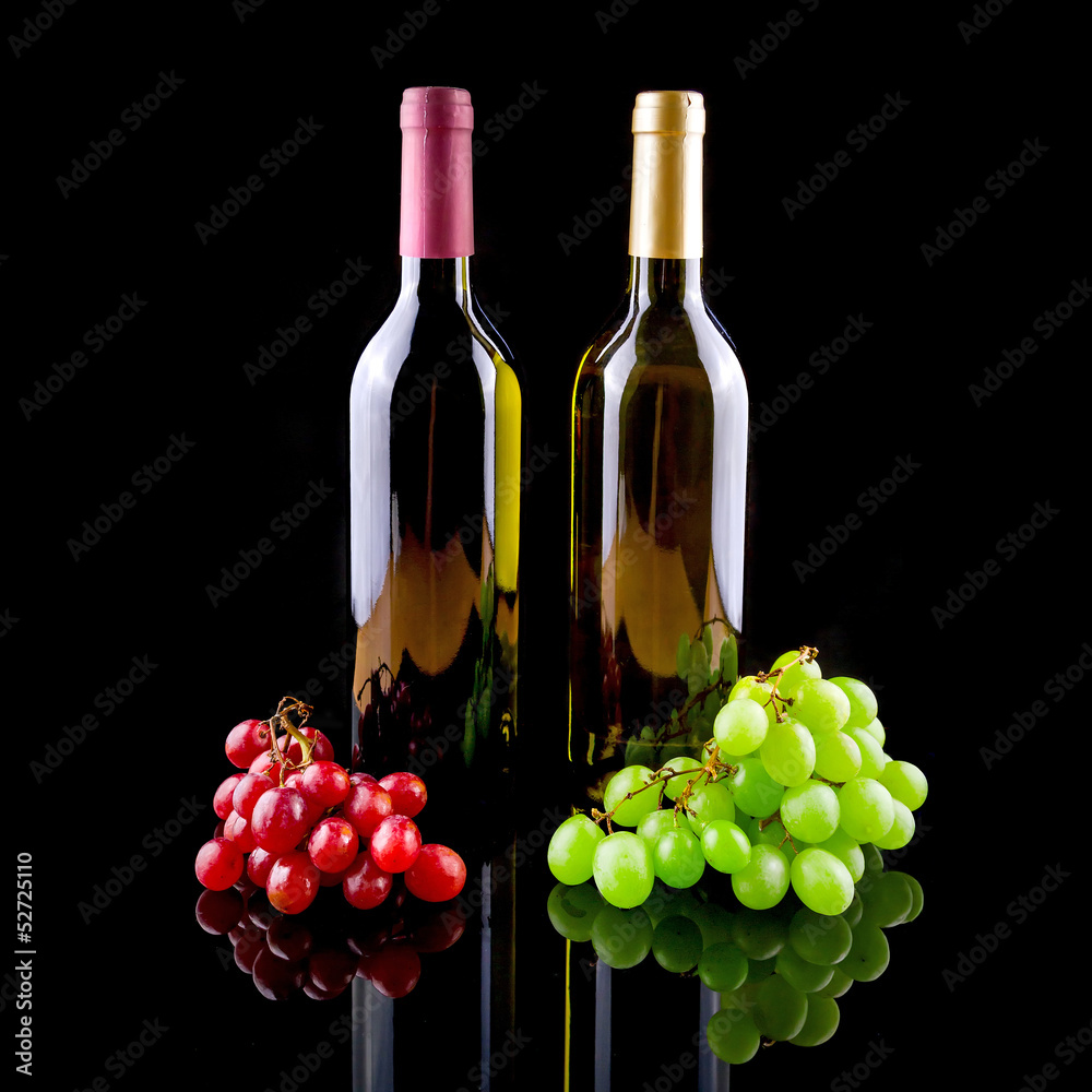 Bottle of red and white wine with grapes over black