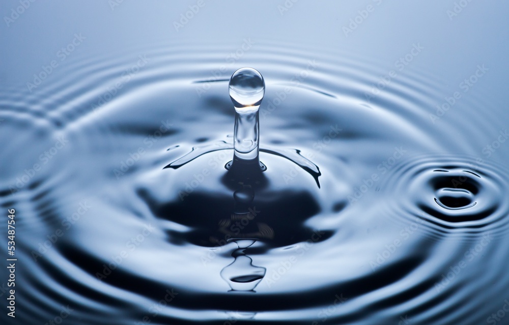 Water drop close up, clear blue background