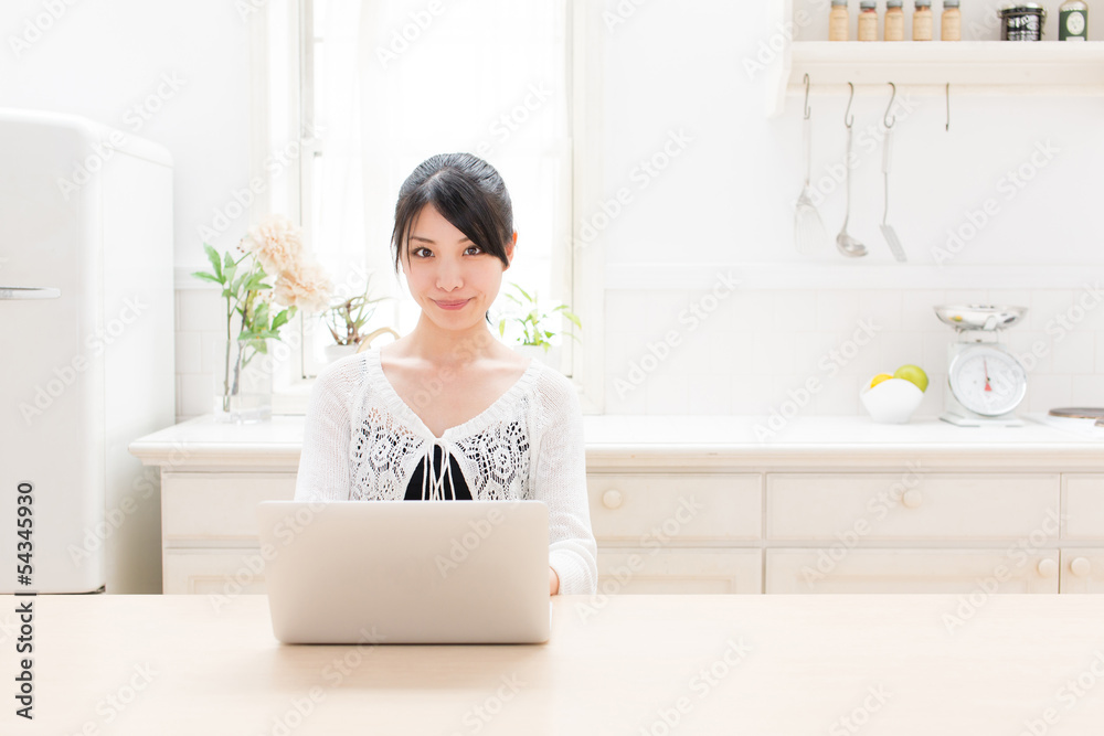 young asian woman using laptop in the kitchen