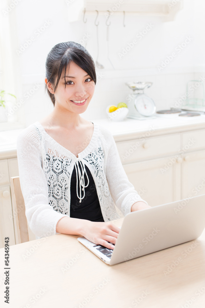 young asian woman using laptop in the kitchen