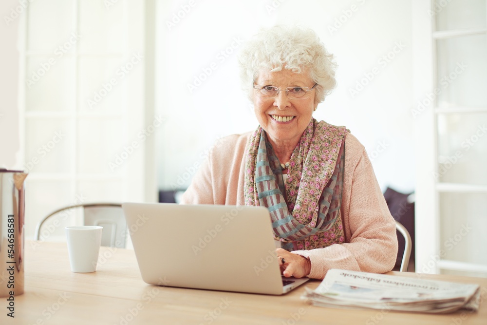 Cheerful Senior Woman at Home with Laptop