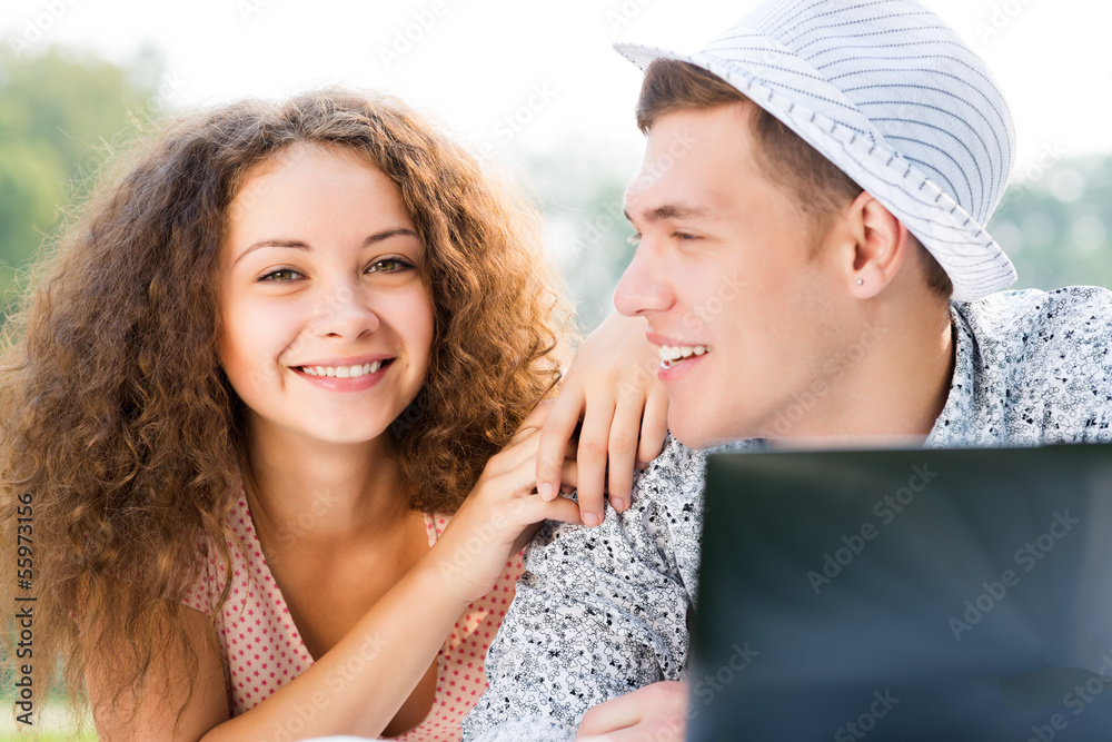 couple lying together in a park with laptop