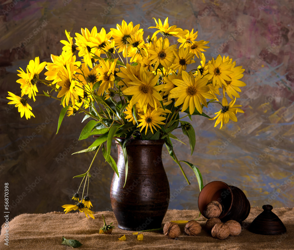 Bunch of bright yellow flowers (rudbeckia) in brown vase and wal