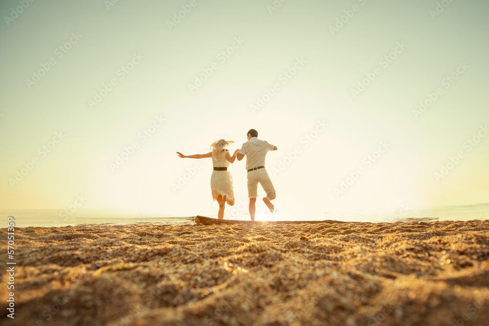 couple jumping to the sea at sunrise