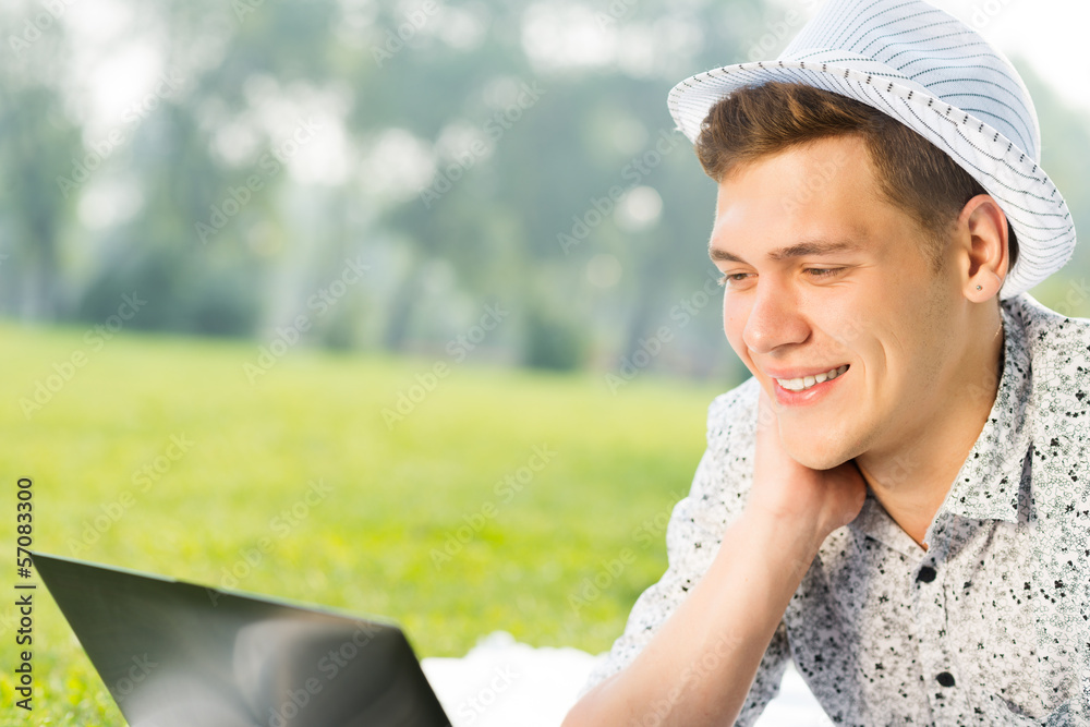 young man working in the park with a laptop