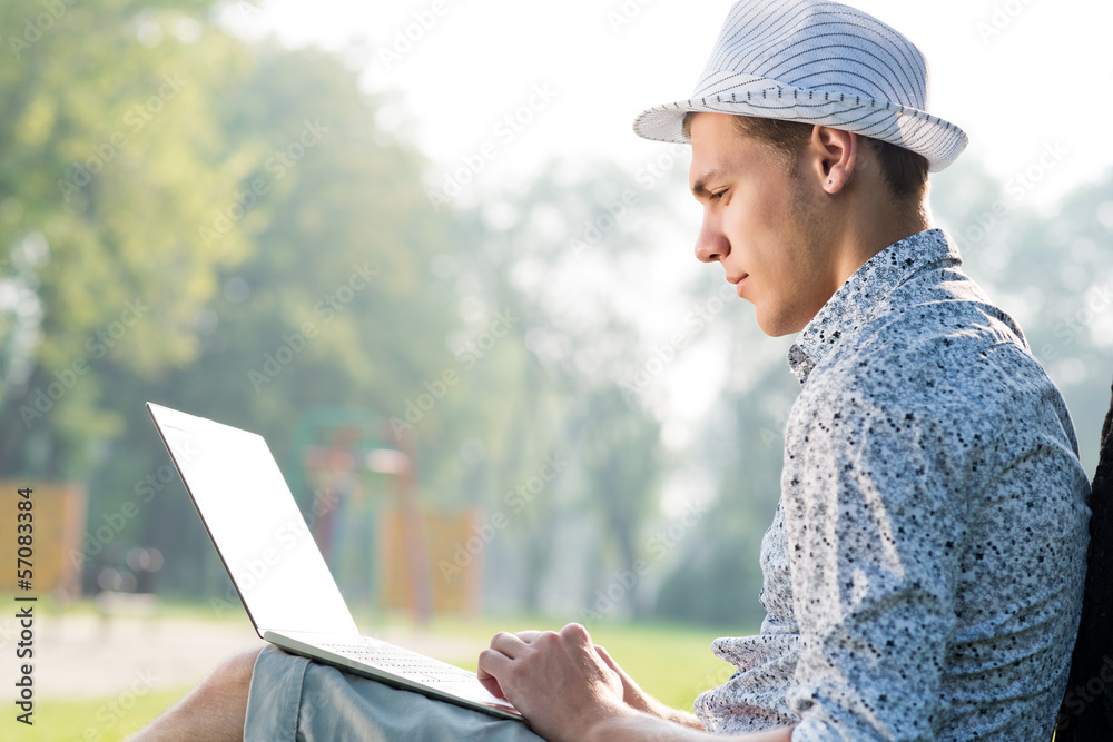 young man working in the park with a laptop