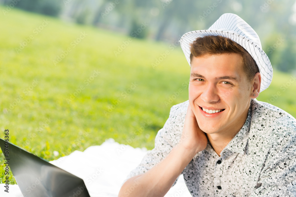 young man working in the park with a laptop