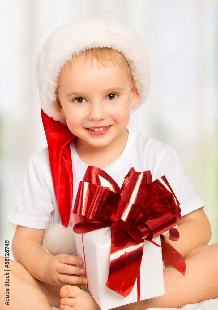 little cute child boy in a Christmas hat with a gift