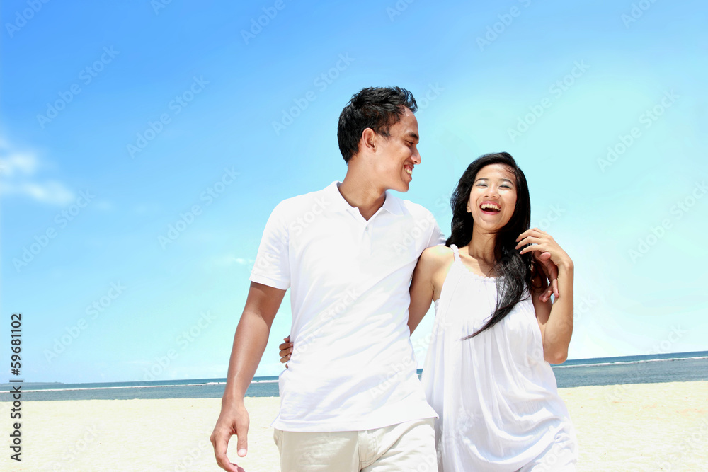 Beach couple in white dress having fun laughing together