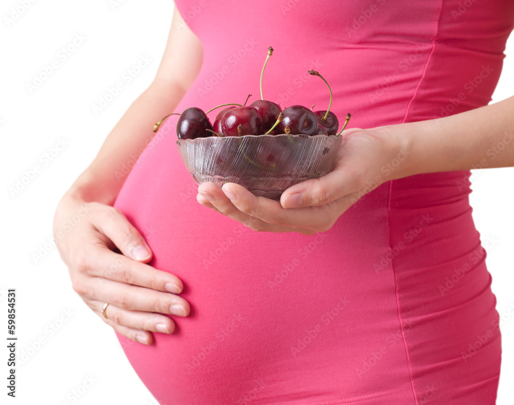 pregnant woman holds a plate with cherry