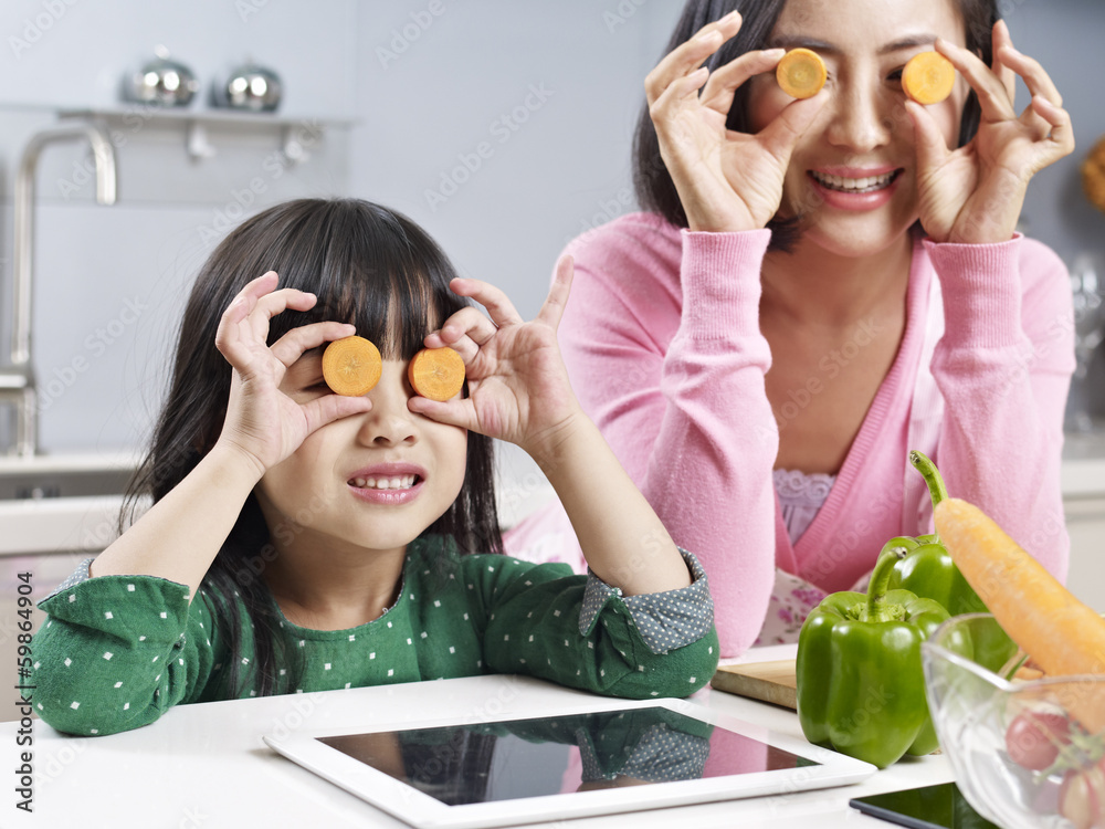 asian mother and daughter playing in kitchen